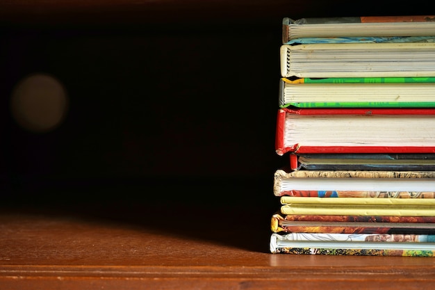 pile of books in wooden cabinet with empty space dark background