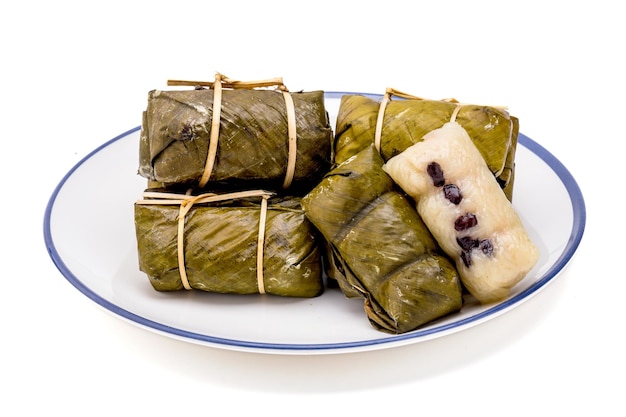 Pile of bundled boiled rice is stacked isolated on white background Thai dessert made with glutinous rice and coconut milk put banana filling wrapped in banana leaves and steamed until cooked