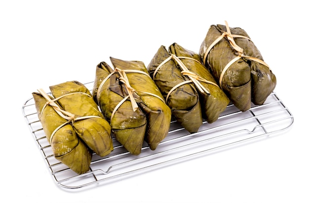 Pile of bundled boiled rice is stacked isolated on white background Thai dessert made with glutinous rice and coconut milk put banana filling wrapped in banana leaves and steamed until cooked