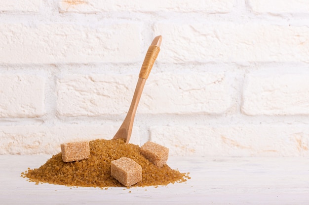 A pile of cane sugar with a stuck wooden spoon