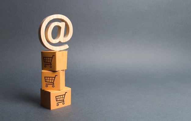 Pile of cardboard boxes with drawing of shopping carts and email symbol commercial AT