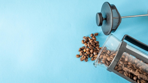 Pile of coffee coming from french press over blue background with copy space or text area