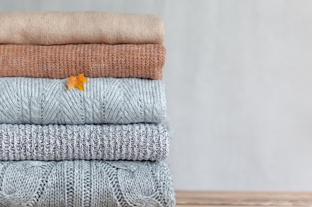 Pile of cozy knitted sweaters on a neutral background Warm concept