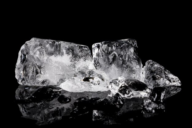 Pile of different ice cubes on reflection table on black background