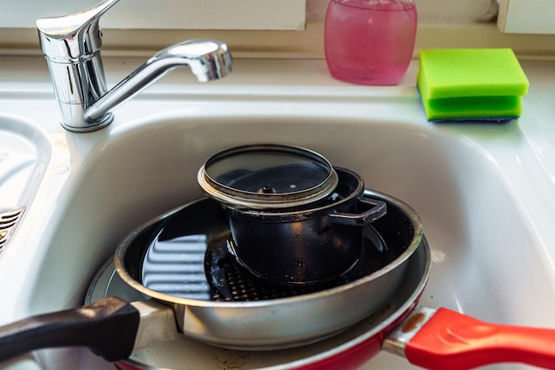 Pile dirty unwashed dishes in kitchen sink