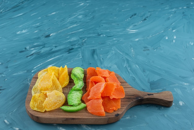 Pile of dried tropical fruits placed on a wooden cutting board .