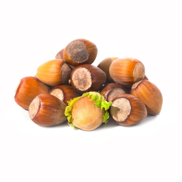 Pile of filbert nuts with green leaf isolated on white