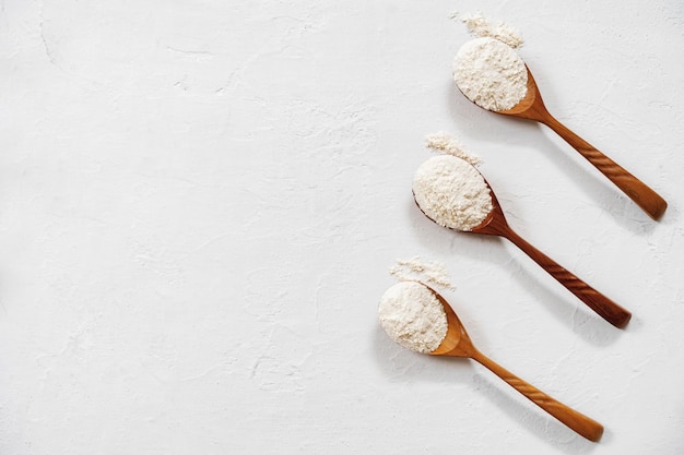 Pile of flour in wooden spoon on white background