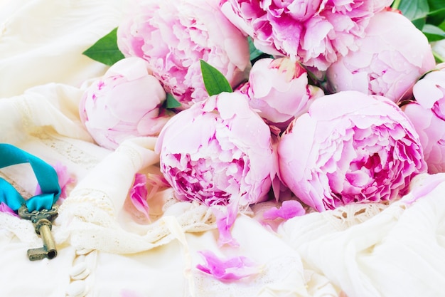 Pile of fresh  pink  peony flowers on vintage lace garment