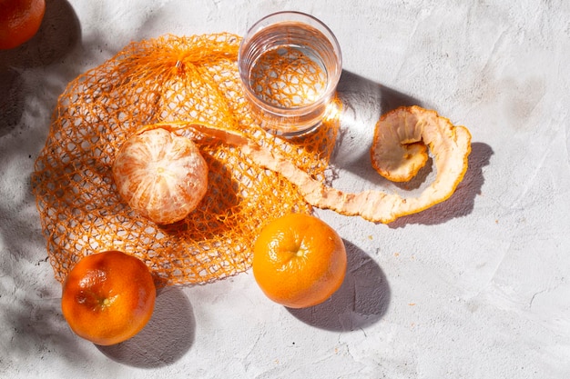 Pile of fresh tangerines and glass with water on the concrete table