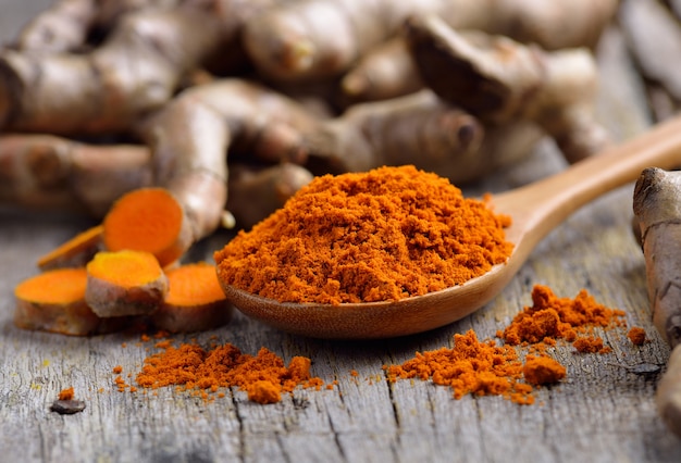 Pile of fresh turmeric roots on wooden table