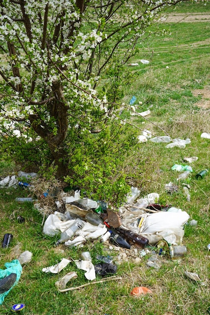 Pile of garbage on the background of green grass on a spring day vertically