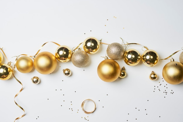 Pile of golden christmas decorations on white background top view of various xmas festive baubles