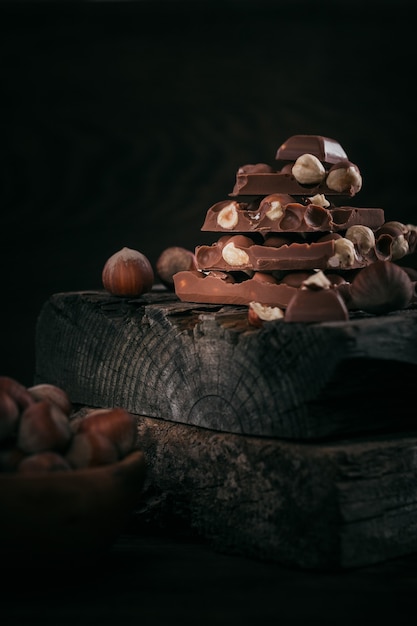 Pile of hazelnut milk chocolate and nuts on dark background