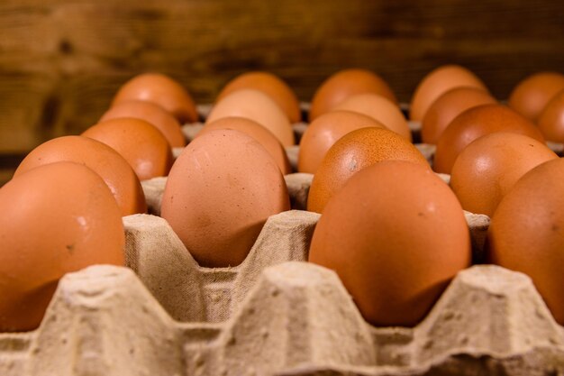 Pile of the hen eggs in paper tray on wooden table