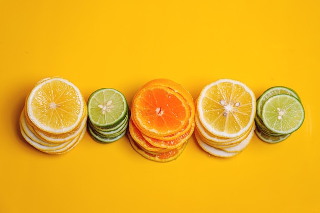 Pile of lemons slice lime slice and orange fruit slice sets on yellow background Flat lay