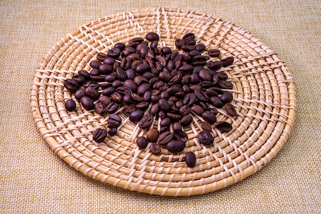 Pile of low quality roasted coffee beans on the rattan tray