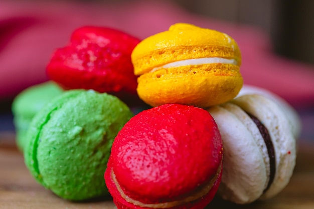 A pile of macarons on a wooden board and a red napkin in the background