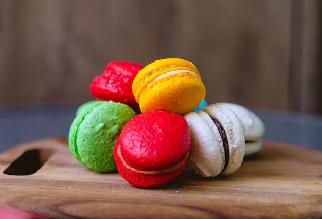 A pile of macarons on a wooden board and a red napkin in the background