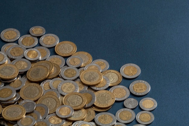 Pile of mexican pesos coins on a blue surface with copy space