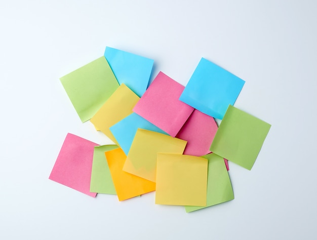 Pile of multicolored paper square stickers on white 