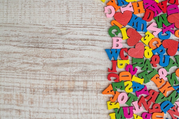 Pile of multicolored small wooden letters for primary education English letters in a chaotic order on wooden table