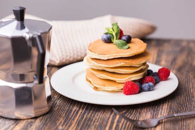 Pile of pancakes with blueberries and raspberries for breakfast on the table