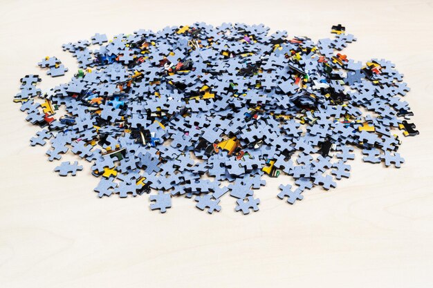 Pile of puzzle pieces on light brown wooden table