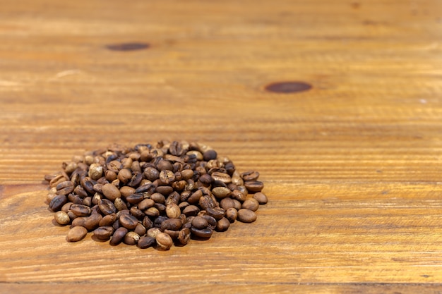 Pile of roasted artesanal gourmet coffee beans pattern on a wood table