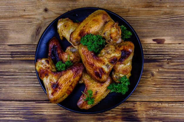 Pile of the roasted chicken wings on plate Top view