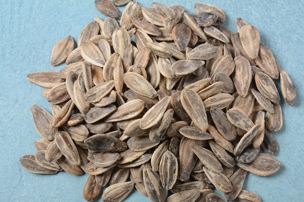 A pile of roasted sunflower seeds on blue background copy space area for a text Food beverage and wallpaper concepts