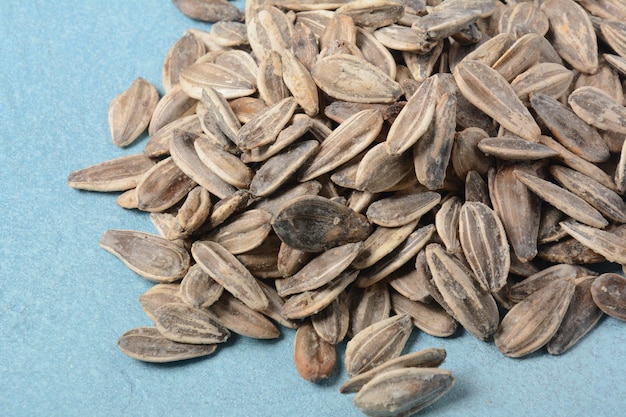 A pile of roasted sunflower seeds on blue background copy space area for a text Food beverage and wallpaper concepts