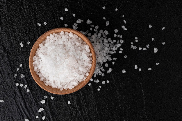 Pile of sea salt on black background top view