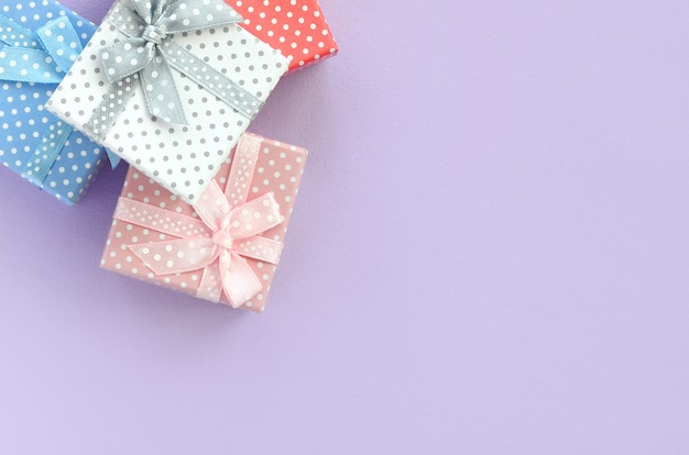 Pile of a small colored gift boxes with ribbons lies on violet 