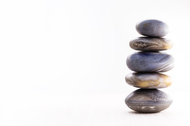 Photo pile of spa stones on the table against a white surface, copy space