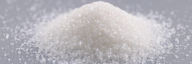 Pile of sugar crystals on grey surface focus on heap of sweet powder to add in dishes