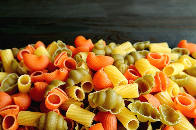 Pile of Three-color Dried Vegeroni Pasta on Black Background with Copy Space