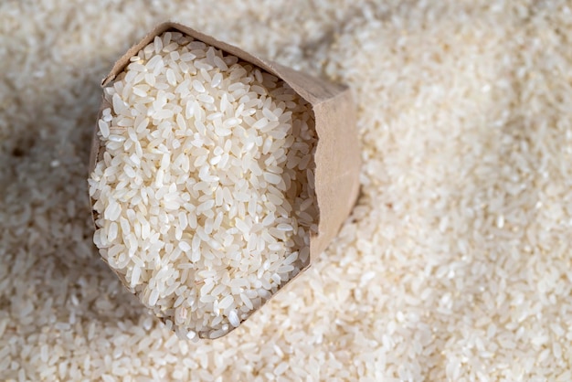 A pile of white rice in a paper bag and on the table