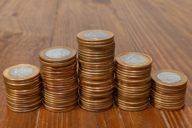 A pile with a lot of Real brazilian money coins stacked as an histogram on a wood table