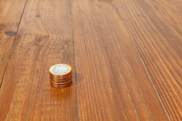 A pile with a lot of Real brazilian money coins stacked on a wood table