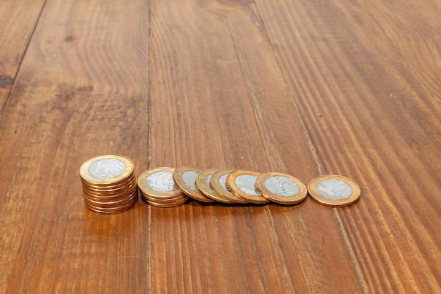 A pile with a lot of Real brazilian money coins stacked on a wood table