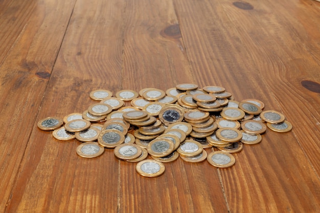 A pile with a lot of Real brazilian money coins on a wood table