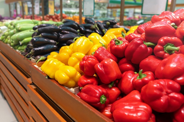 Piles of bell peppers organized at the counter of a supermarket or grocery store. red, orange and yellow bell peppers