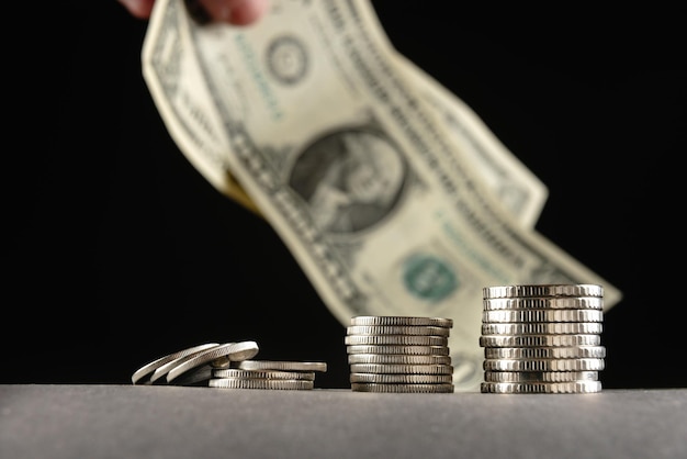 Piles of coins in a stack of different denominations on a black background and a us bill of sale on 