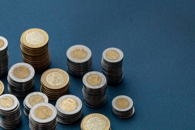 Piles of Mexican pesos coins arranged in the corner of the image with copy space and a blue background