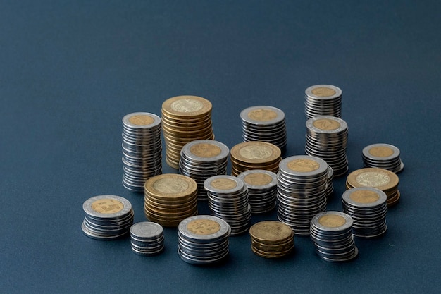 Piles of Mexican pesos coins of different denominations isolated with blue background