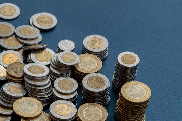 Piles of Mexican pesos coins of different denominations isolated with blue background