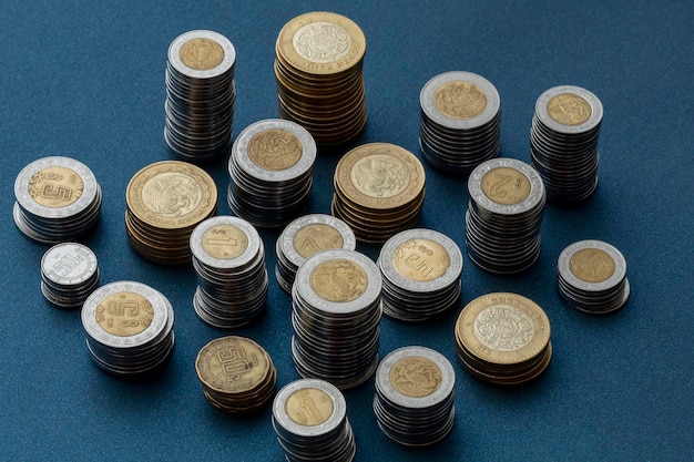 Piles of Mexican pesos coins isolated at the center of the image with a blue background