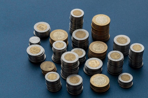 Piles of Mexican pesos coins isolated at the center of the image with a blue background