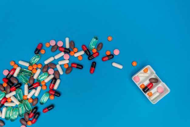 Pill dispenser with multicolored pills on blue background